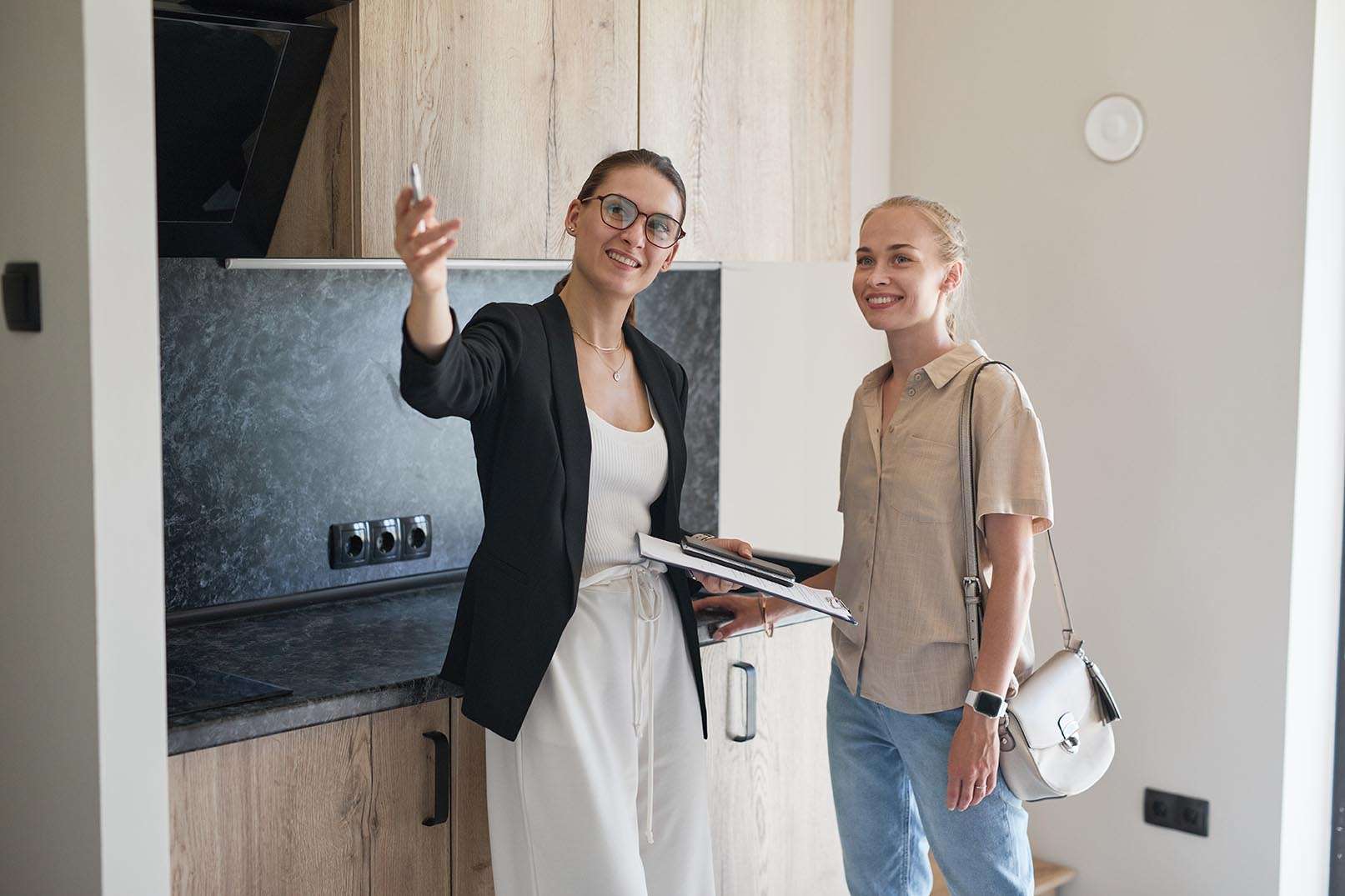 Waist up portrait of female real estate agent giving apartment tour to young woman buying new house
